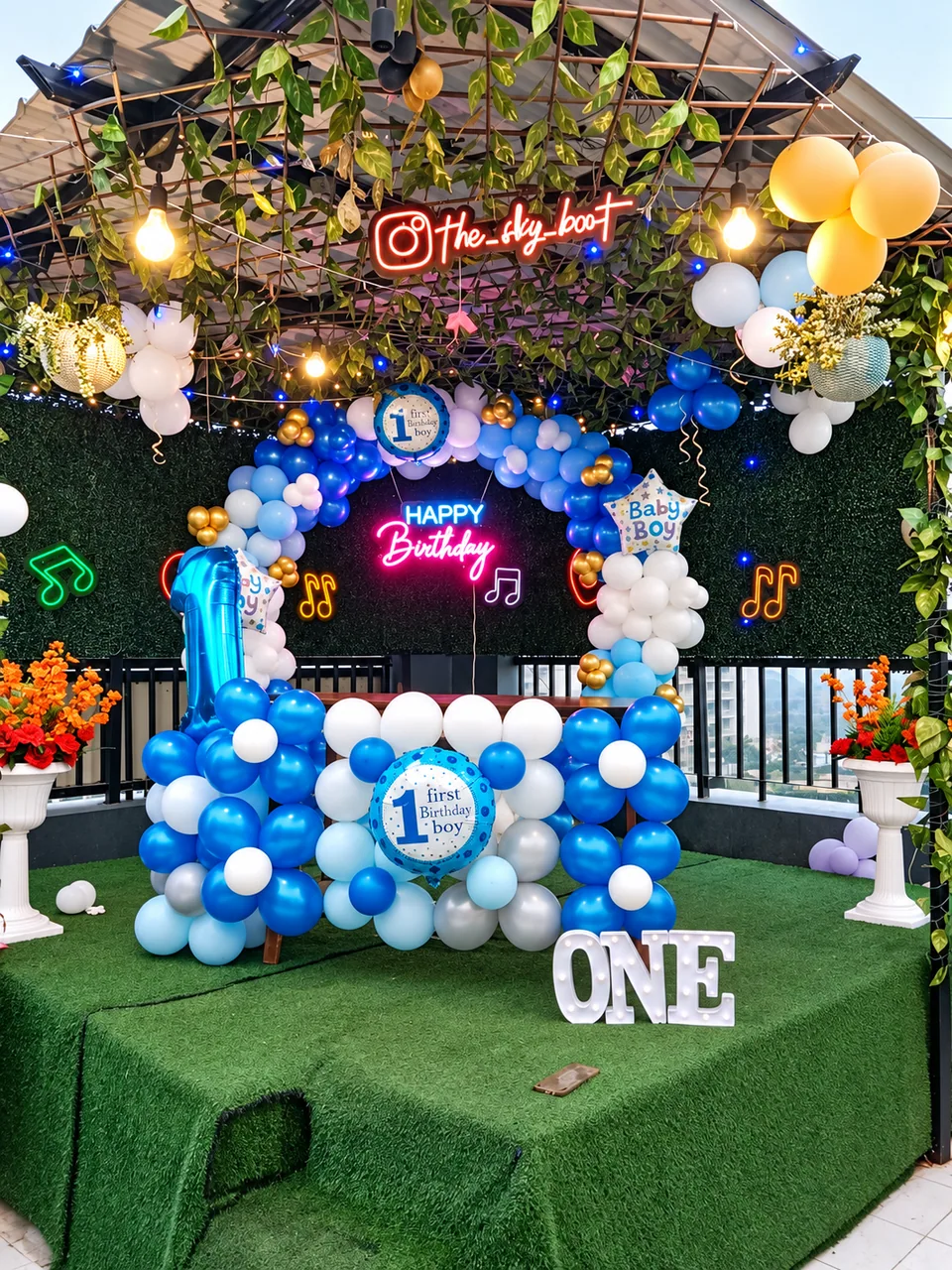 Blue and white first birthday balloon installation with illuminated ONE letters