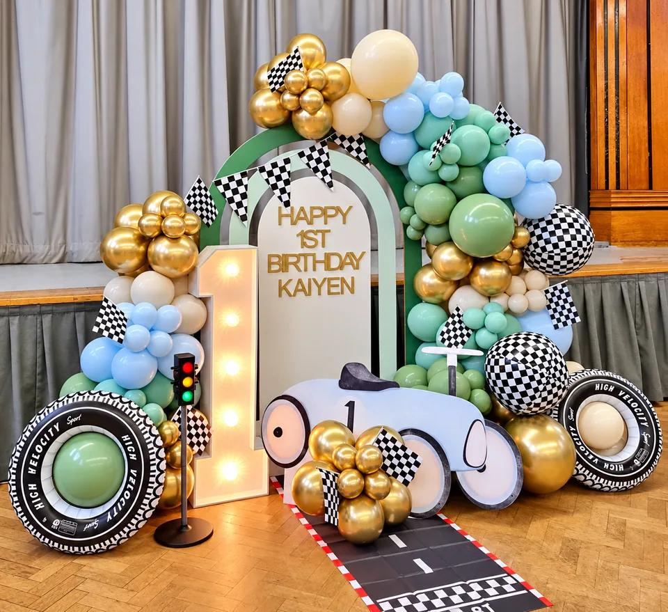Pastel racing birthday setup with chequered flags, car prop and illuminated number one